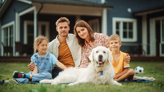 A family relaxing on the lawn with their dog outside their home